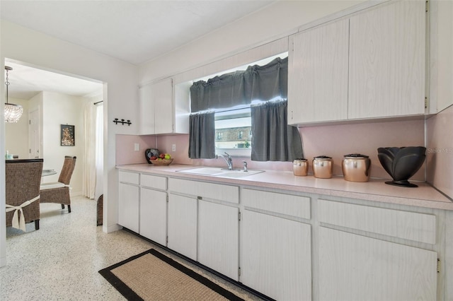 kitchen featuring white cabinetry, sink, and pendant lighting