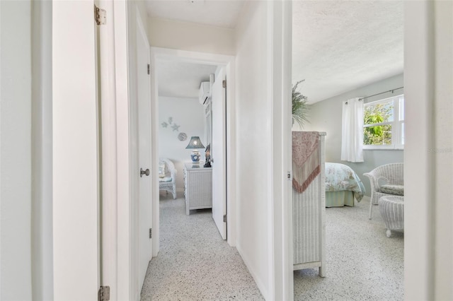 hallway with an AC wall unit and a textured ceiling