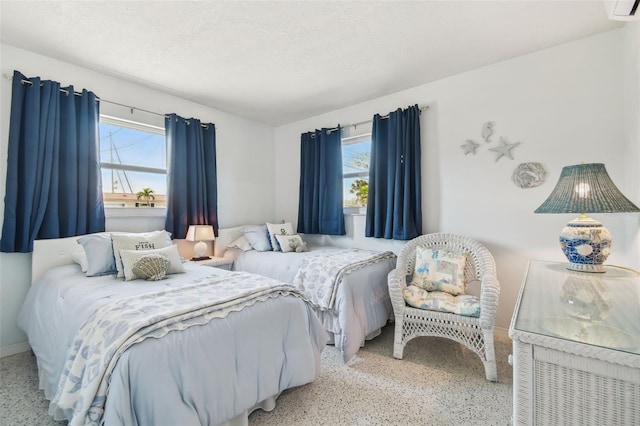 bedroom with a wall mounted air conditioner and a textured ceiling