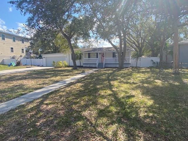 view of front of home with covered porch, a front lawn, an attached garage, and fence