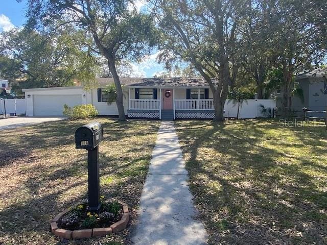 single story home featuring driveway, an attached garage, covered porch, fence, and a front lawn