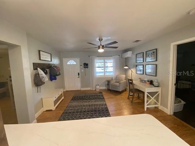 entryway with ceiling fan, a wall mounted AC, and dark hardwood / wood-style flooring