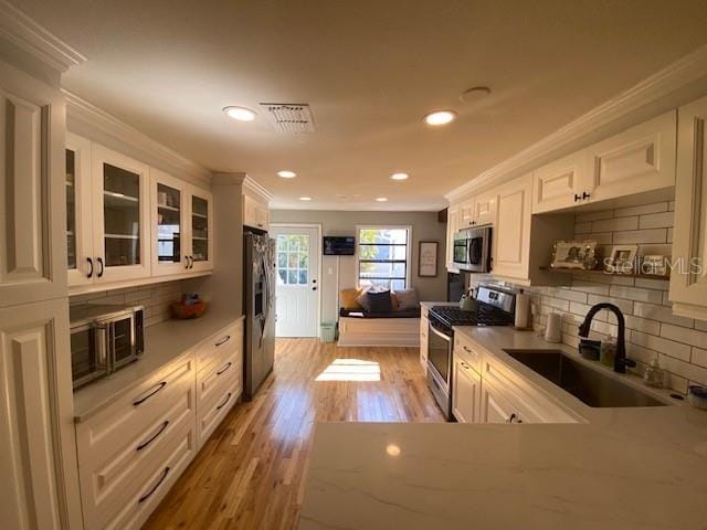 kitchen featuring stainless steel appliances, white cabinetry, sink, and ornamental molding