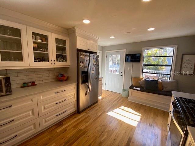 kitchen featuring backsplash, light wood-type flooring, white cabinets, and appliances with stainless steel finishes