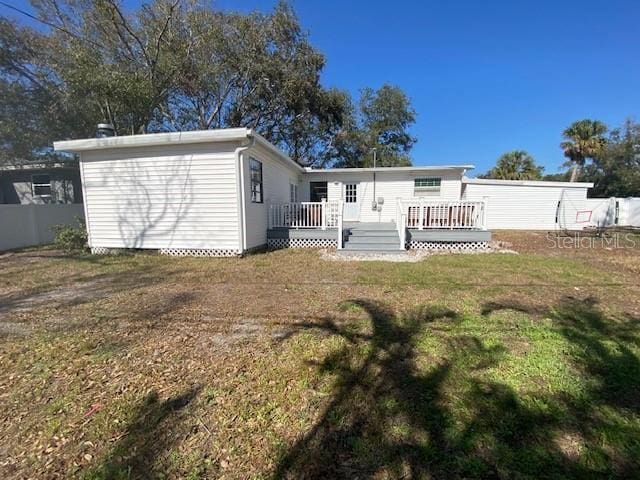 rear view of property featuring fence, a deck, and a lawn