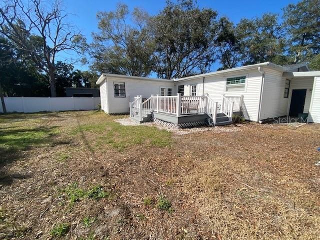 back of property with fence and a wooden deck