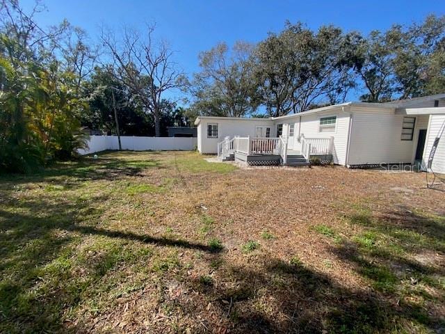 rear view of property with a yard, fence, and a deck