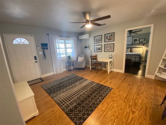 foyer featuring a wall mounted air conditioner, ceiling fan, baseboards, and wood finished floors