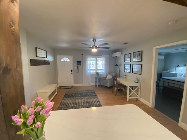 foyer featuring visible vents, a wall mounted AC, wood finished floors, and a ceiling fan