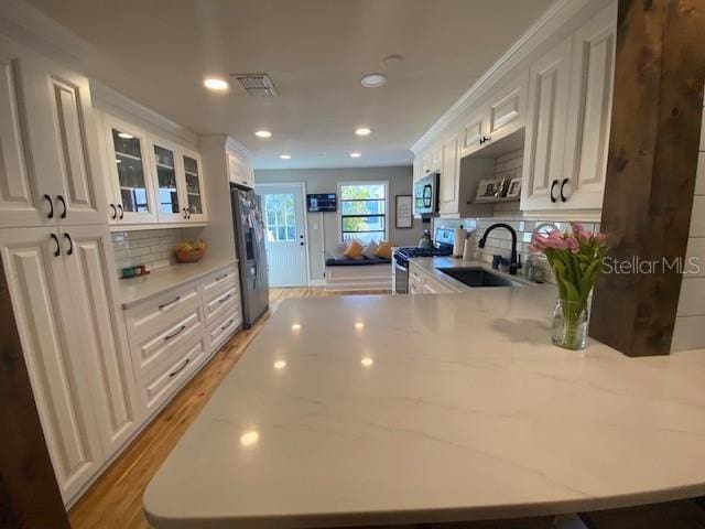 kitchen featuring a peninsula, white cabinetry, appliances with stainless steel finishes, and a sink