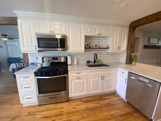 kitchen featuring light wood-type flooring, appliances with stainless steel finishes, light countertops, and a sink