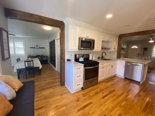 kitchen with stainless steel appliances, light countertops, white cabinets, and decorative backsplash