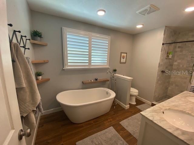 bathroom featuring toilet, wood finished floors, a sink, a freestanding bath, and tiled shower