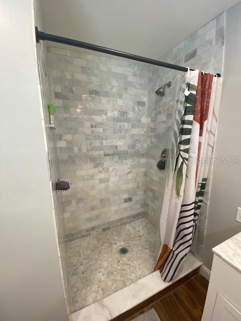 full bath featuring a shower stall, wood finished floors, and vanity