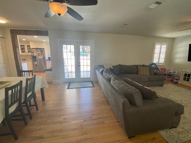 living room featuring light wood-type flooring, french doors, visible vents, and ceiling fan