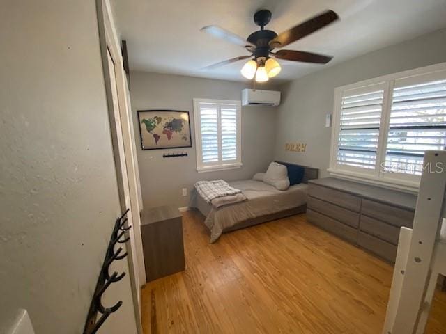 unfurnished bedroom with light wood-type flooring, a wall mounted air conditioner, and ceiling fan