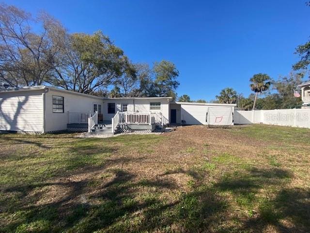 rear view of property featuring fence, a deck, and a yard