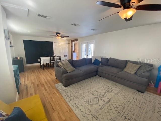 living room featuring ceiling fan, visible vents, wood finished floors, and french doors