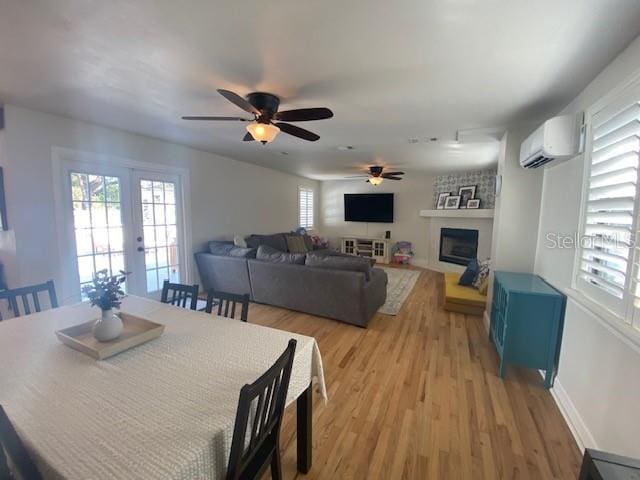 dining space featuring french doors, plenty of natural light, light wood finished floors, and a wall mounted AC