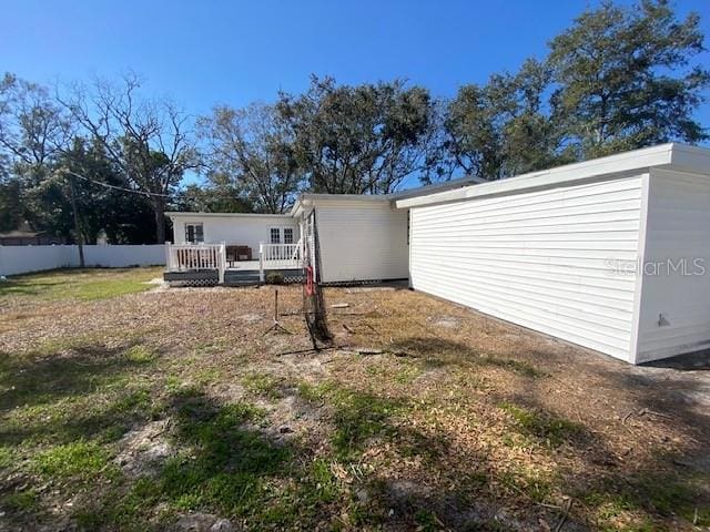 rear view of house featuring fence and a wooden deck