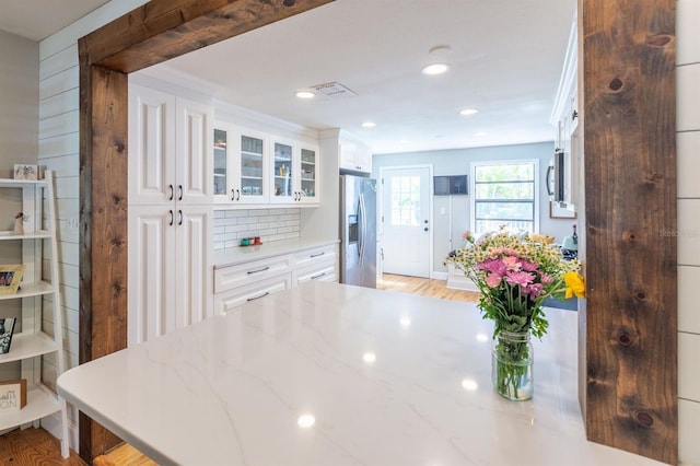 kitchen with tasteful backsplash, white cabinets, appliances with stainless steel finishes, and glass insert cabinets