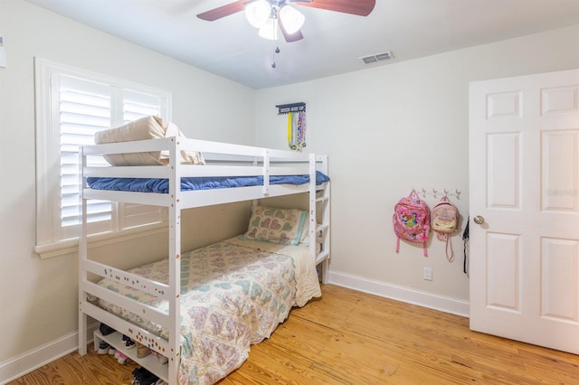 bedroom with ceiling fan, wood finished floors, visible vents, and baseboards