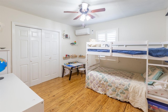 bedroom featuring a closet, a wall mounted AC, a ceiling fan, and wood finished floors
