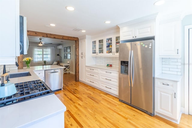 kitchen with light wood finished floors, stainless steel appliances, light countertops, and a sink