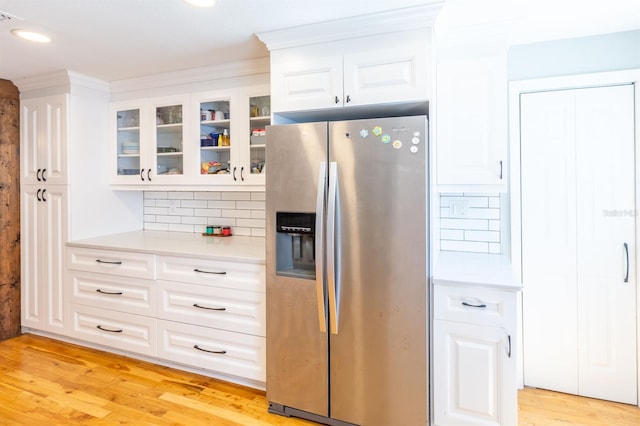 kitchen with backsplash, stainless steel fridge, light wood-type flooring, and light countertops