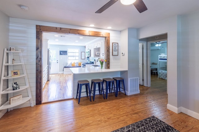 kitchen featuring a kitchen bar, light wood-type flooring, visible vents, and ceiling fan