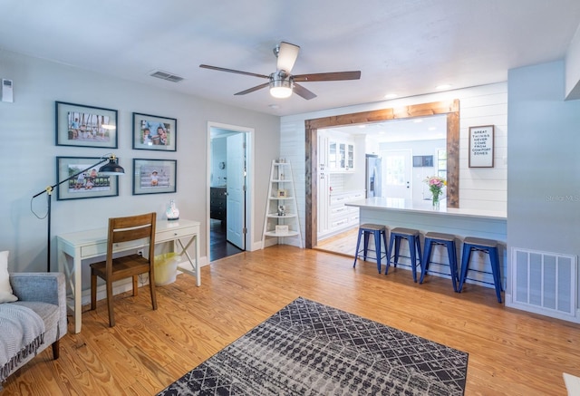 interior space featuring baseboards, visible vents, a ceiling fan, and light wood-style floors
