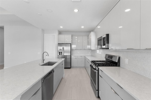 kitchen with white cabinetry, stainless steel appliances, sink, and tasteful backsplash