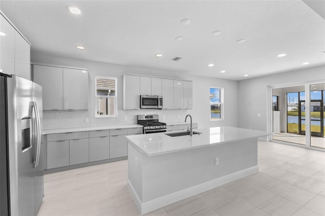 kitchen with a kitchen island with sink, sink, tasteful backsplash, and stainless steel appliances