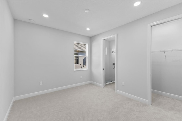 unfurnished bedroom featuring a walk in closet, light colored carpet, and a closet