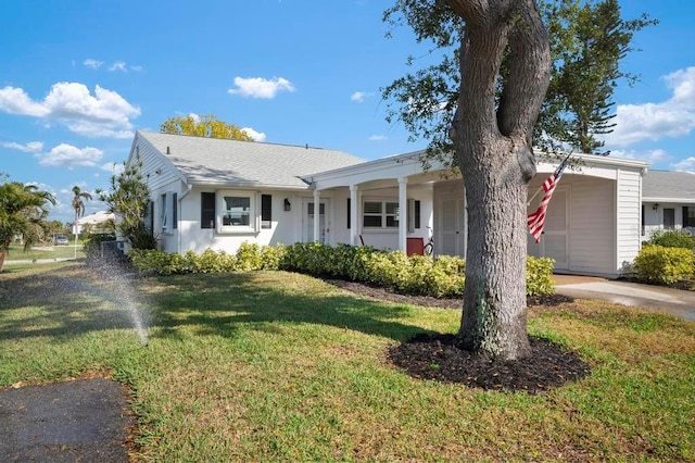 ranch-style house with a shingled roof, a front lawn, and stucco siding