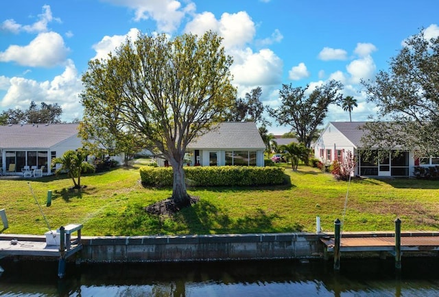 rear view of house featuring a sunroom, a water view, and a lawn