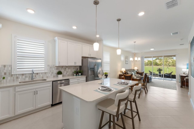 kitchen with stainless steel appliances, white cabinetry, a kitchen island, and sink