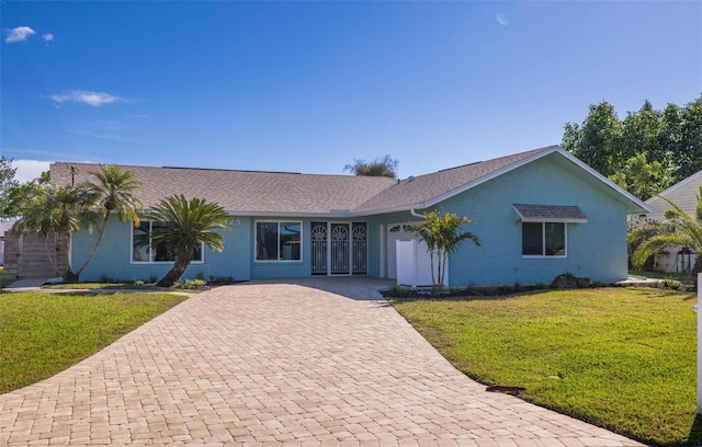 single story home with a front lawn, decorative driveway, an attached garage, and stucco siding