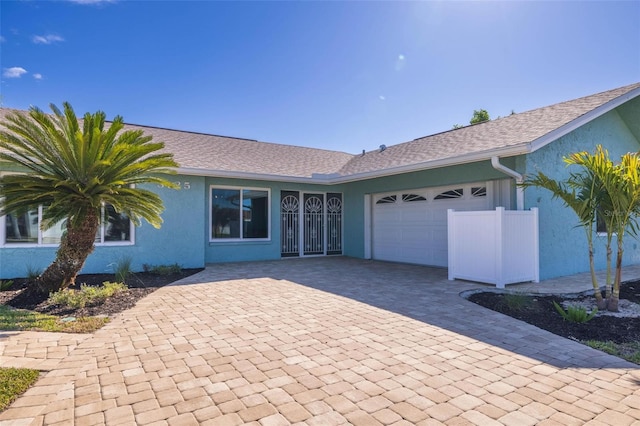 ranch-style house featuring a garage, decorative driveway, and stucco siding