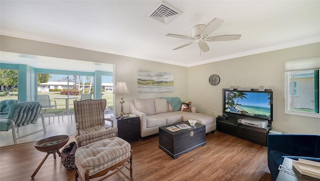 living room featuring ornamental molding, dark wood finished floors, visible vents, and a ceiling fan