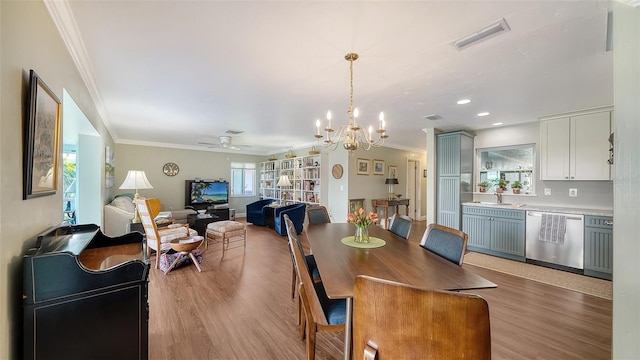 dining room with light wood-type flooring, visible vents, crown molding, and ceiling fan with notable chandelier