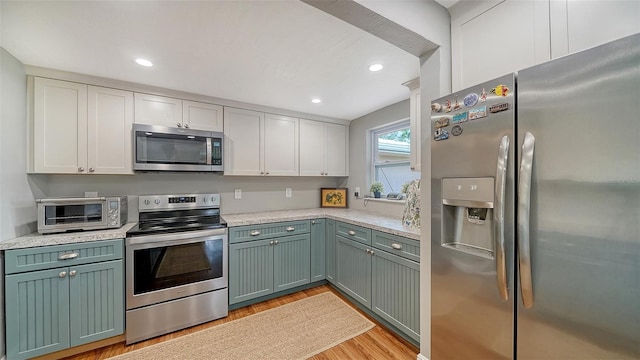 kitchen featuring white cabinets, stainless steel appliances, light wood-style flooring, and a toaster