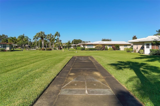 view of property's community featuring a lawn and shuffleboard