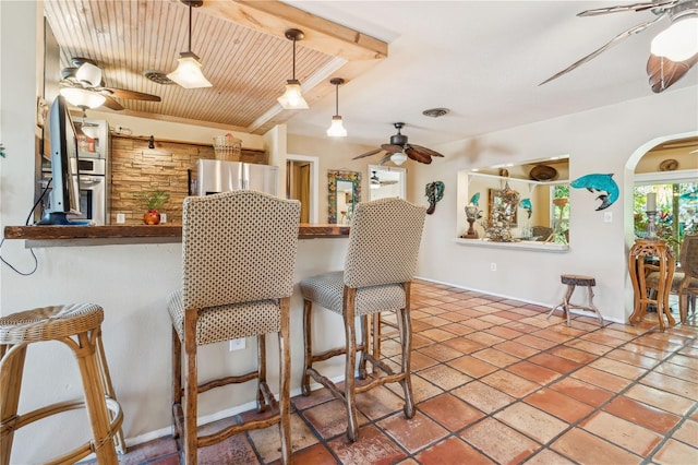 kitchen featuring pendant lighting, a breakfast bar area, stainless steel fridge, and ceiling fan