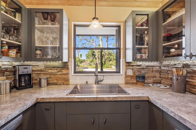 kitchen featuring decorative backsplash, dishwasher, sink, and hanging light fixtures