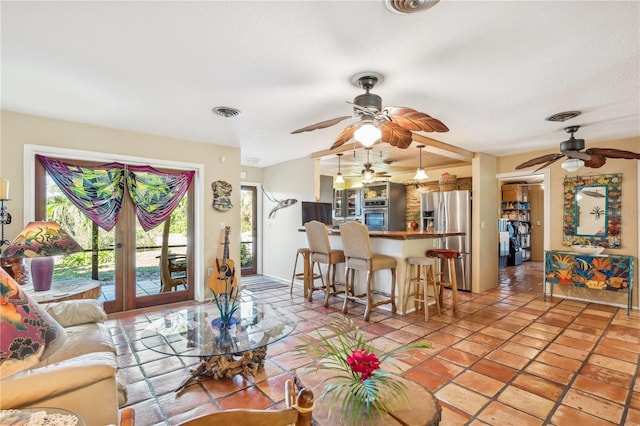 tiled living room with french doors, plenty of natural light, and a textured ceiling