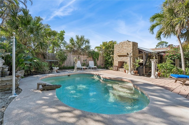 view of swimming pool with a patio and an outdoor stone fireplace