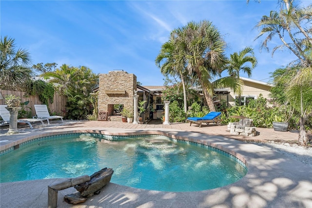 view of swimming pool featuring a patio and an outdoor stone fireplace