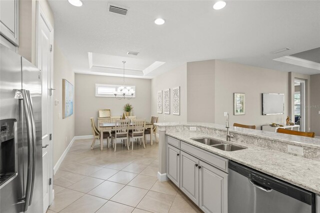5556 Cantucci St, Nokomis, FL 34275 - kitchen with stainless steel appliances, a sink, a raised ceiling, baseboards, and a chandelier