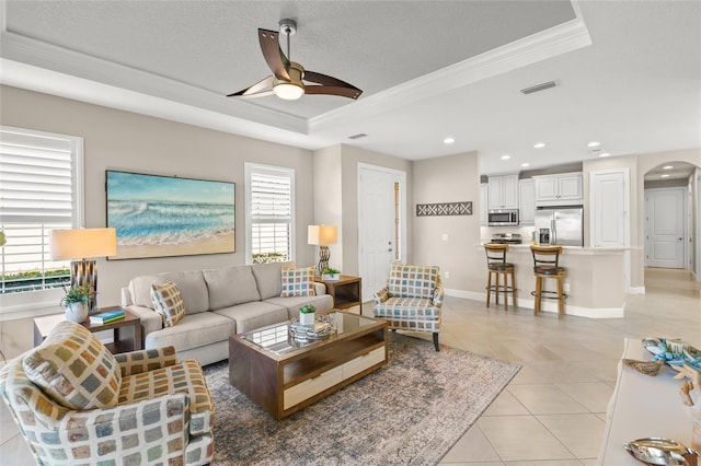 5556 Cantucci St, Nokomis, FL 34275 - living room featuring a tray ceiling, crown molding, ceiling fan, arched walkways, and light tile patterned flooring
